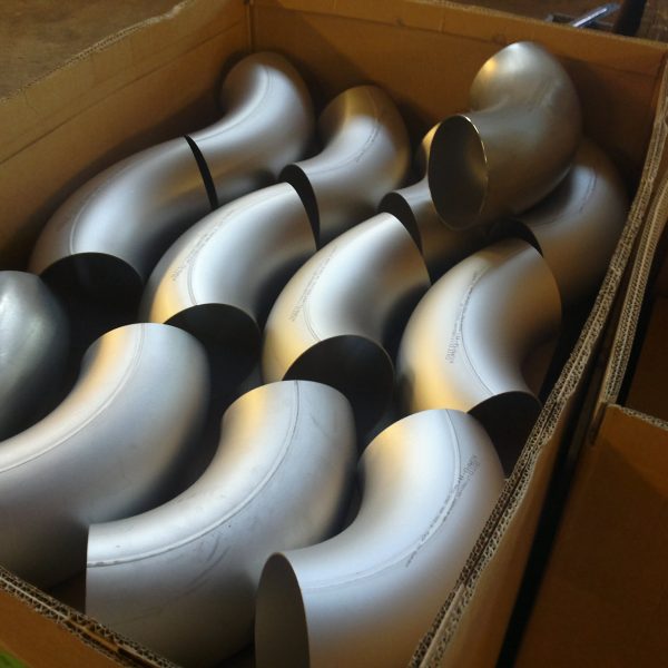 Box of stainless steel pipe elbows prepared for industrial installation by a piping installation company