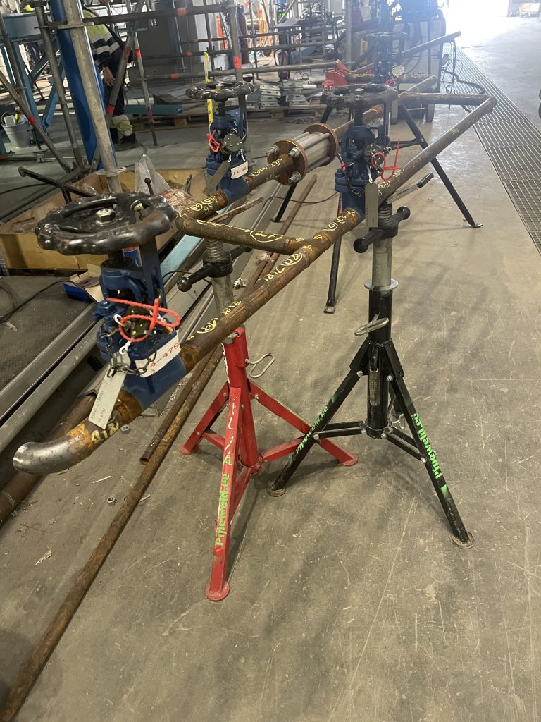 Industrirør plassert på støttende bukker etter sveising og montering, klart for bruk i industrielle installasjoner.