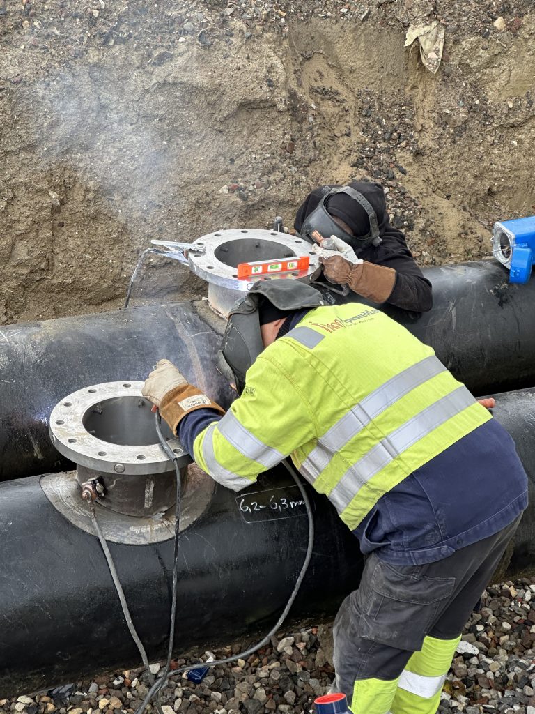 Sveiser arbeider med Hot Tapping, sveiser en flens på et aktivt fjernvarmerør for tilkobling uten avbrudd.