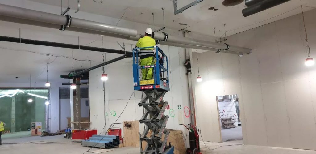 Arbetare på saxlift förbereder sig för rörmontage i Stockholm.