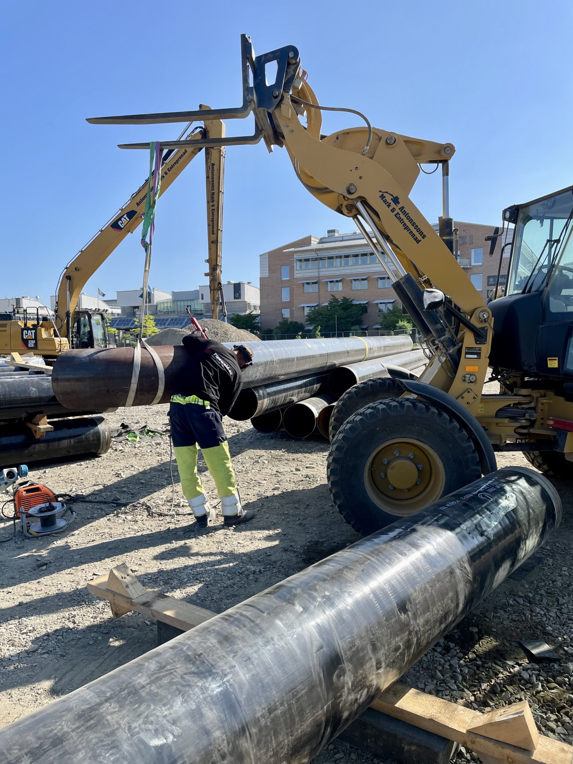 Mechanical Contractor — welder aligning a pipe with help from a forklift.