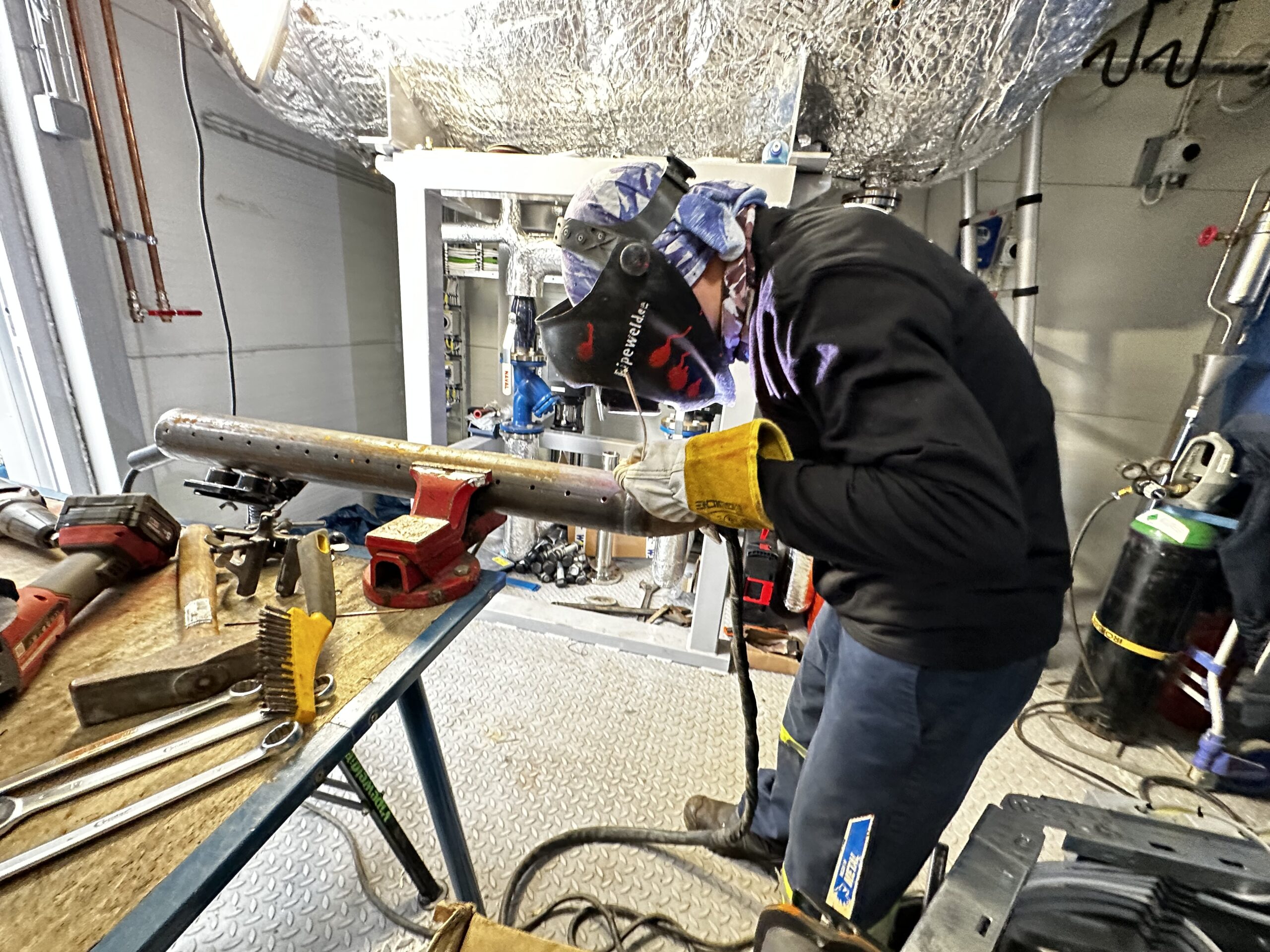 Mechanical Contractor — welder joining a pipe on a modular steam boiler, pipe from water feed tank.