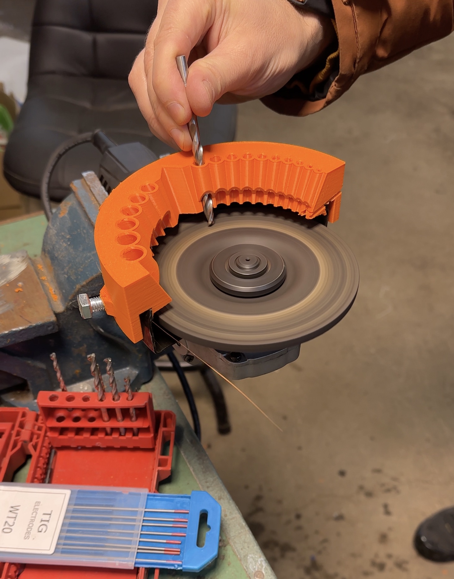 Image of an innovative drill bit sharpener attachment for angle grinders, designed to sharpen drill bits and prepare tungsten for TIG welding. Compatible with top brands like Bosch, Makita, and Milwaukee, featuring adjustable guard height for various discs